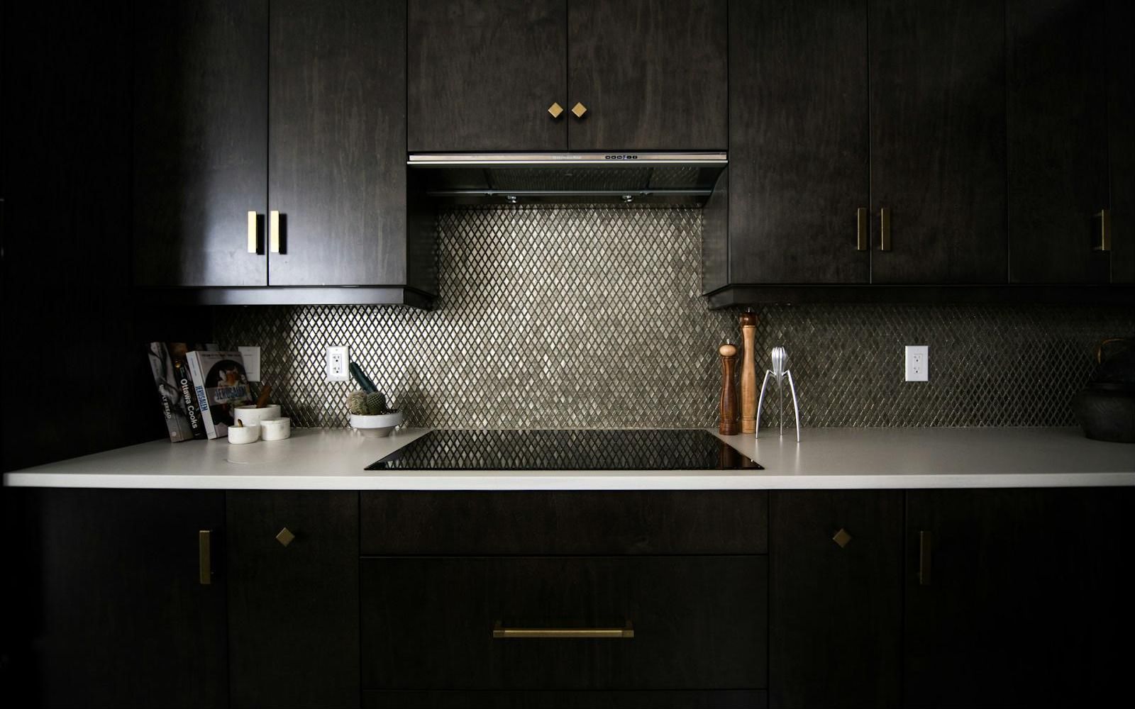 Dark wood kitchen cabinets with brass pulls and mosaic backsplash