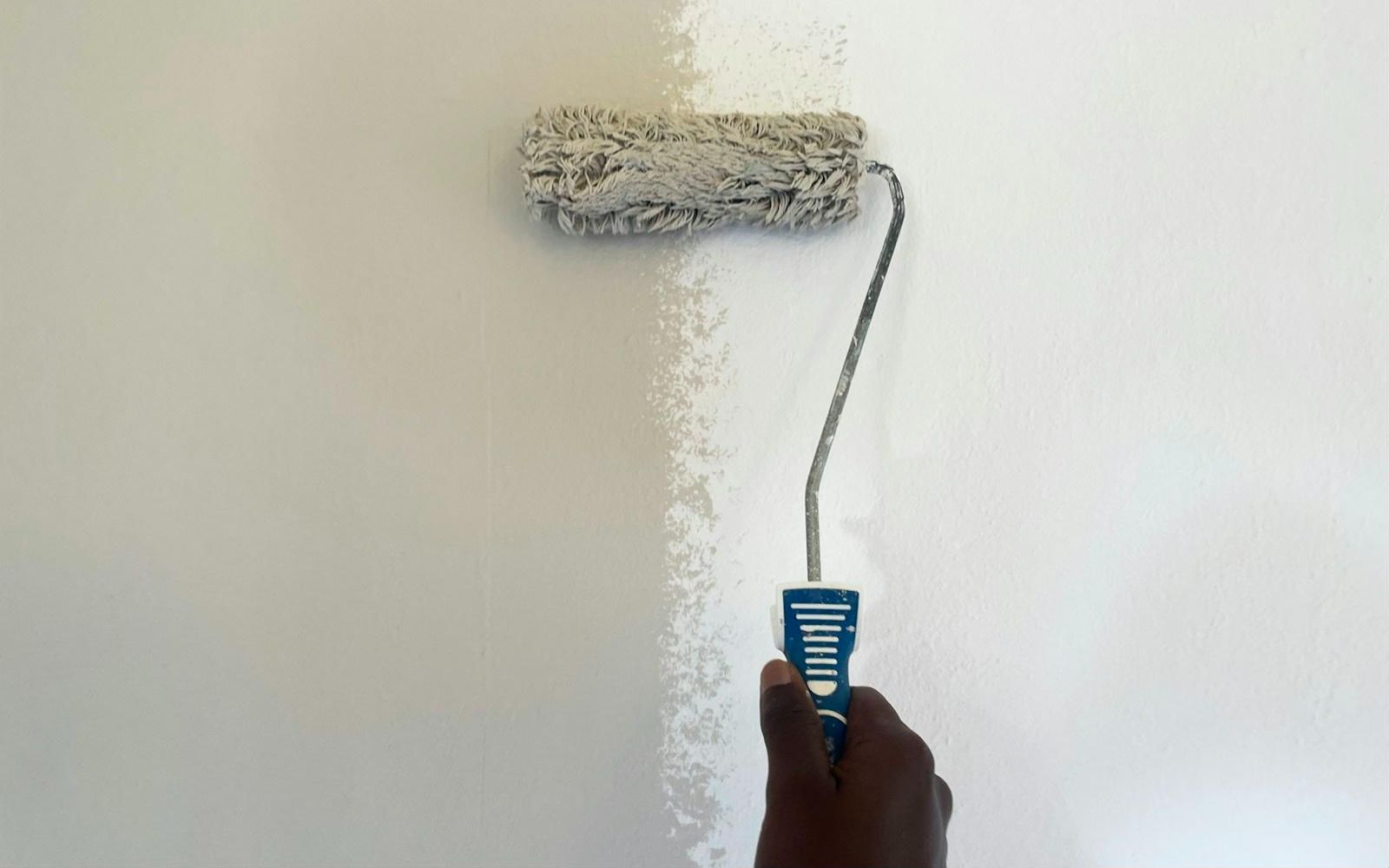 Paint roller applying a fresh coat to a wall